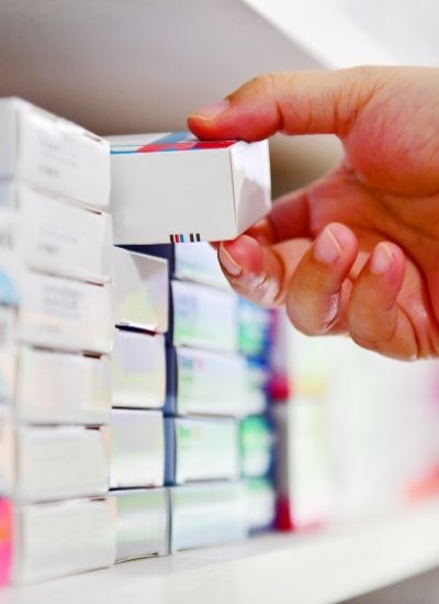 A close up of a customer's hands remove a pill pack from the shelf