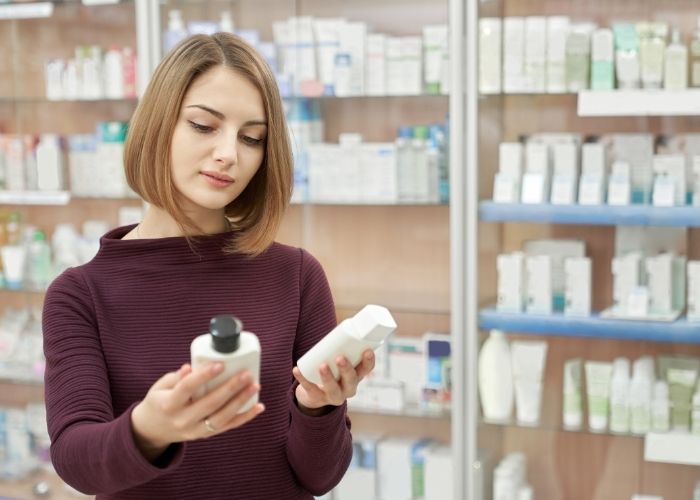 A customer in a pharmacy comparing two different products that are in bottles
