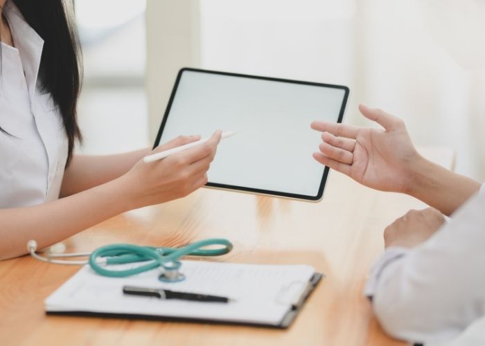 A doctor asking for a patient's signature using a tablet